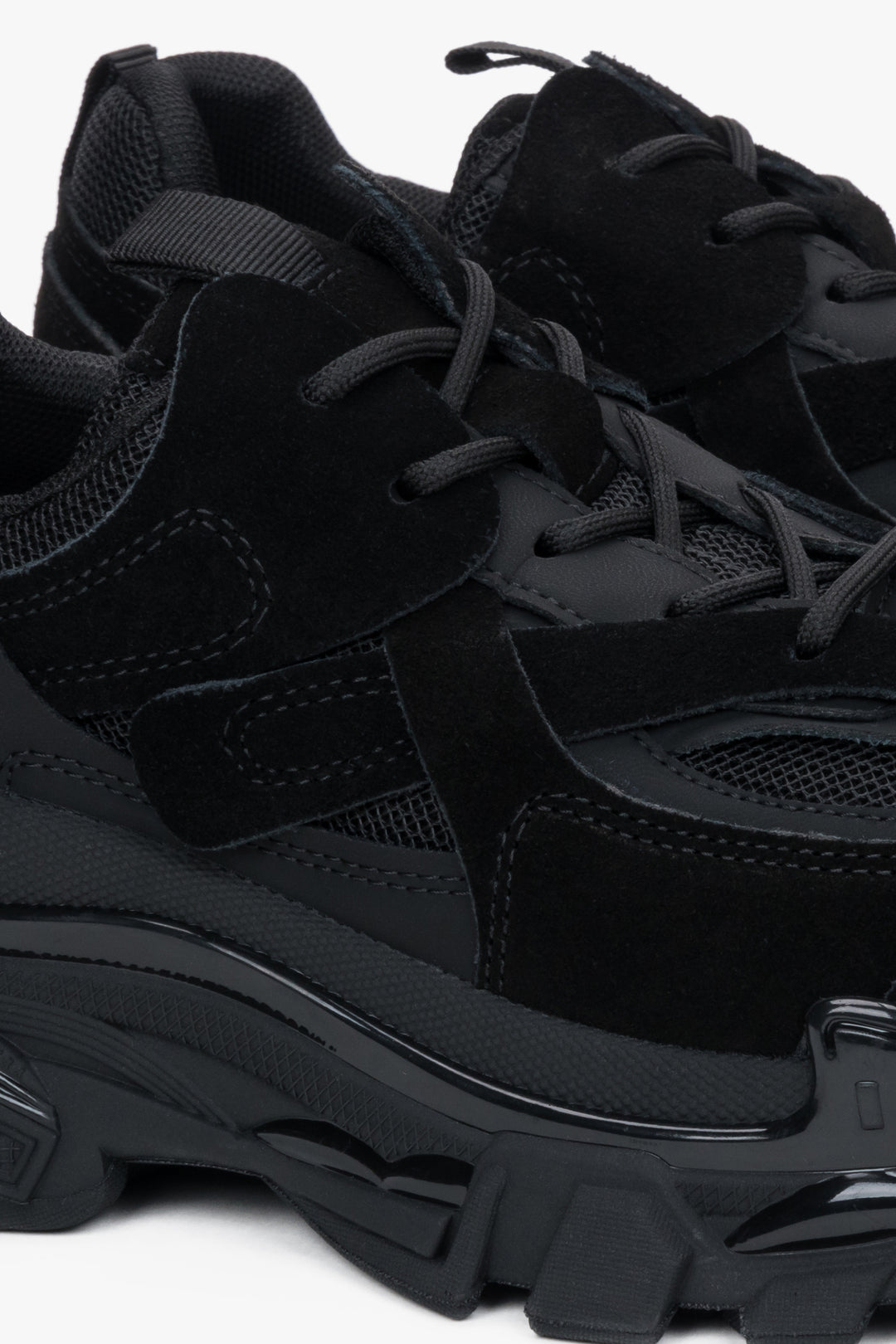 Nahaufnahme des schwarzen Sneakers mit Fokus auf den Materialmix aus Velours und Mesh sowie die markante Profilsohle 