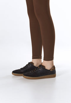Model trägt die schwarzen Sneaker zu einer braunen Leggings