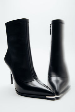 Schräge Frontalansicht der schwarzen Damen-Stiefeletten aus Echtleder auf weißem Hintergrund