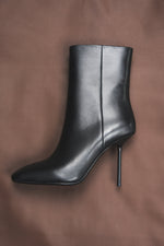 Künstlerische Inszenierung der schwarzen Damen-Stiefelette aus Echtleder auf braunem Seidenstoff 