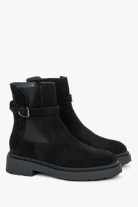 Schräge Frontalansicht der schwarzen Velours-Stiefeletten mit dekorativem Riemen