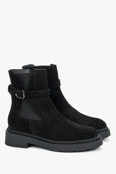 Schräge Frontalansicht der schwarzen Velours-Stiefeletten mit dekorativem Riemen