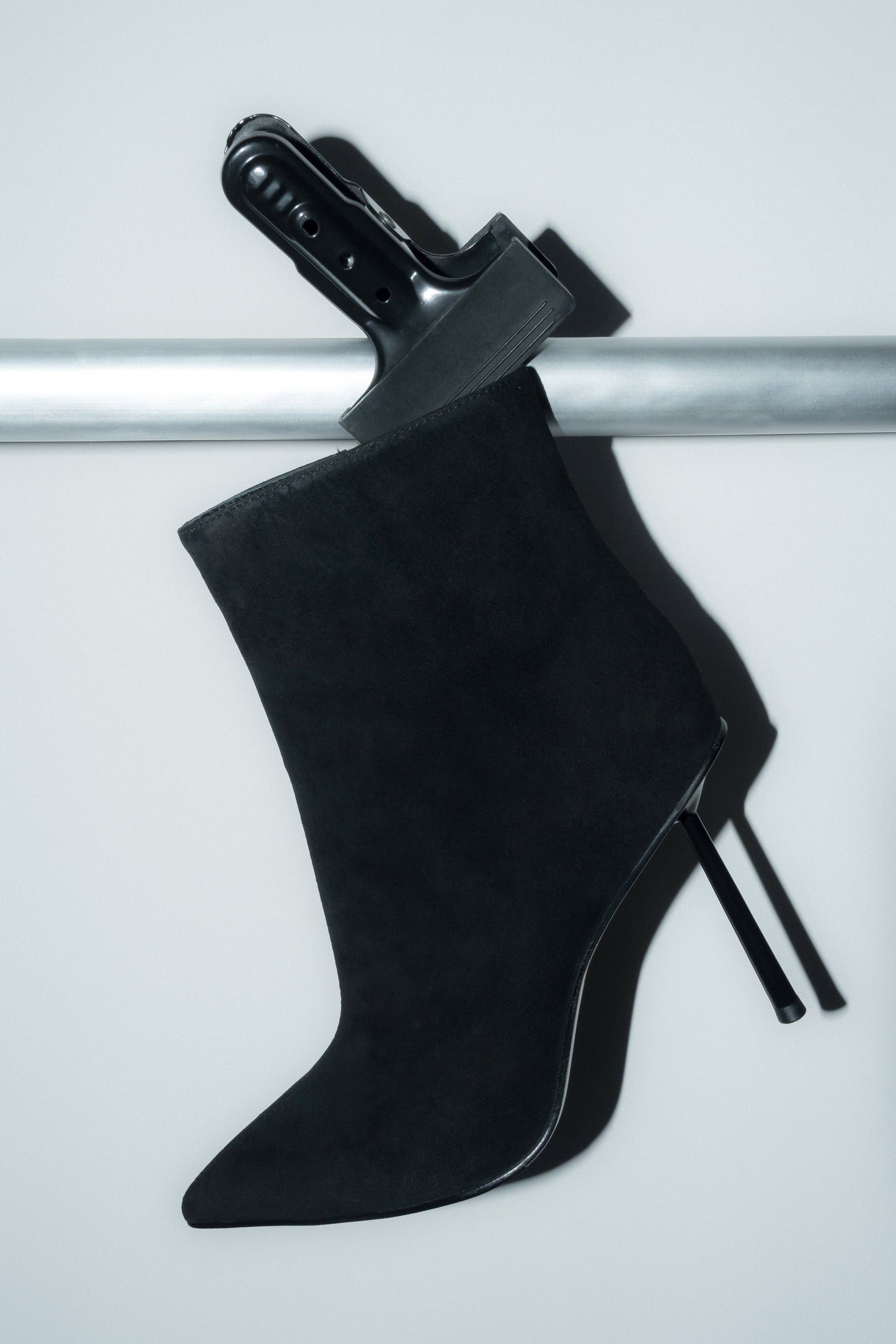 Inszenierte Darstellung der schwarzen Damen-Stiefelette aus Velours auf einer silbernen Stange 