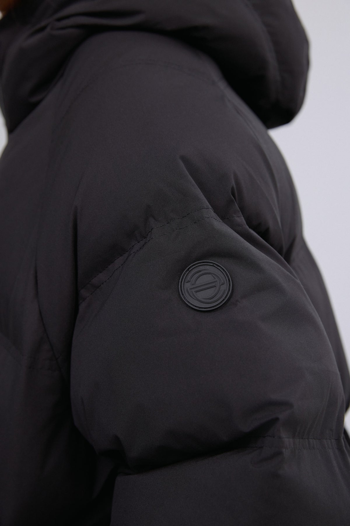 Nahaufnahme des Ärmels der schwarzen Jacke mit dezentem Knopfdetail