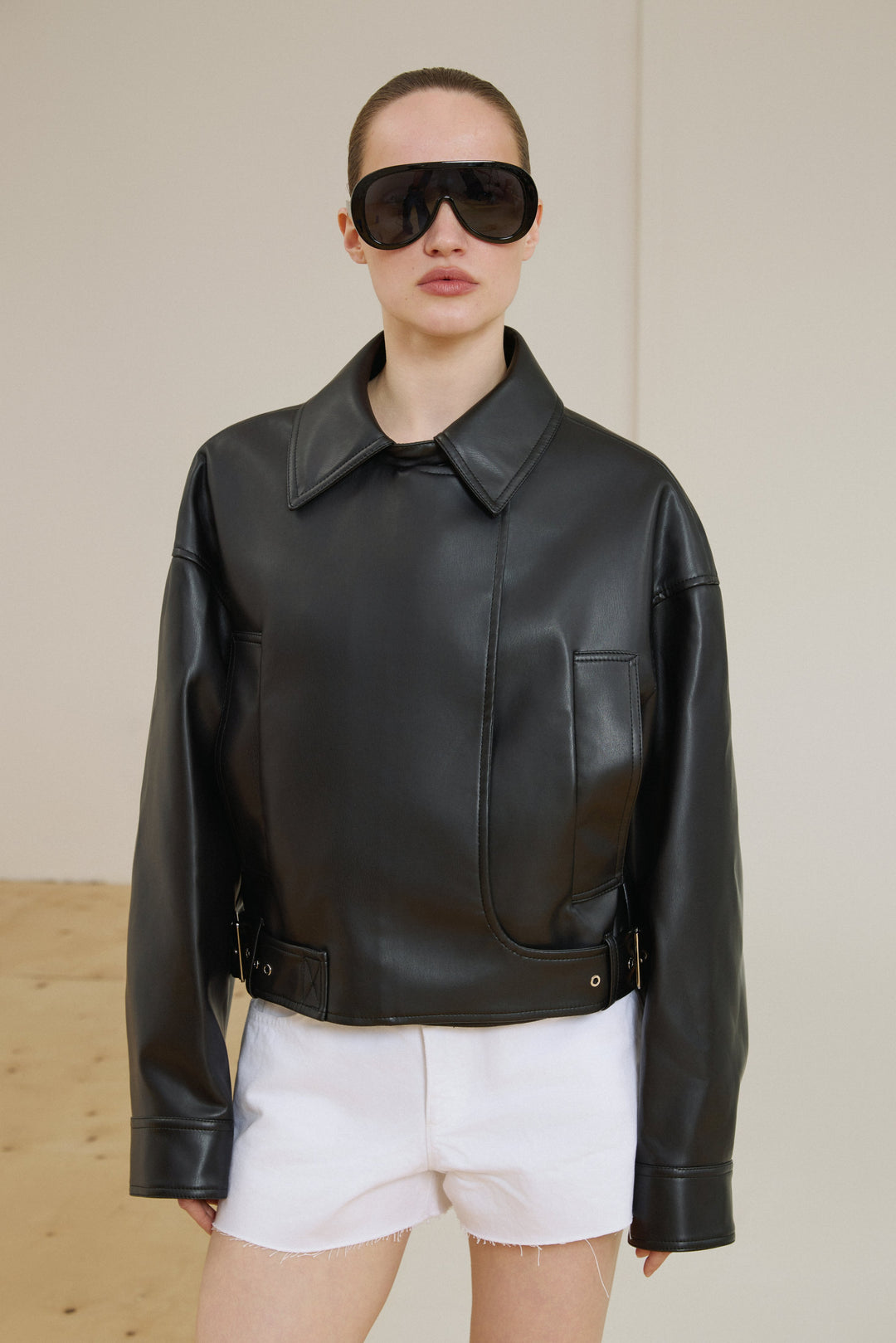 Model mit Sonnenbrille trägt schwarze Oversize-Bikerjacke Vorderansicht