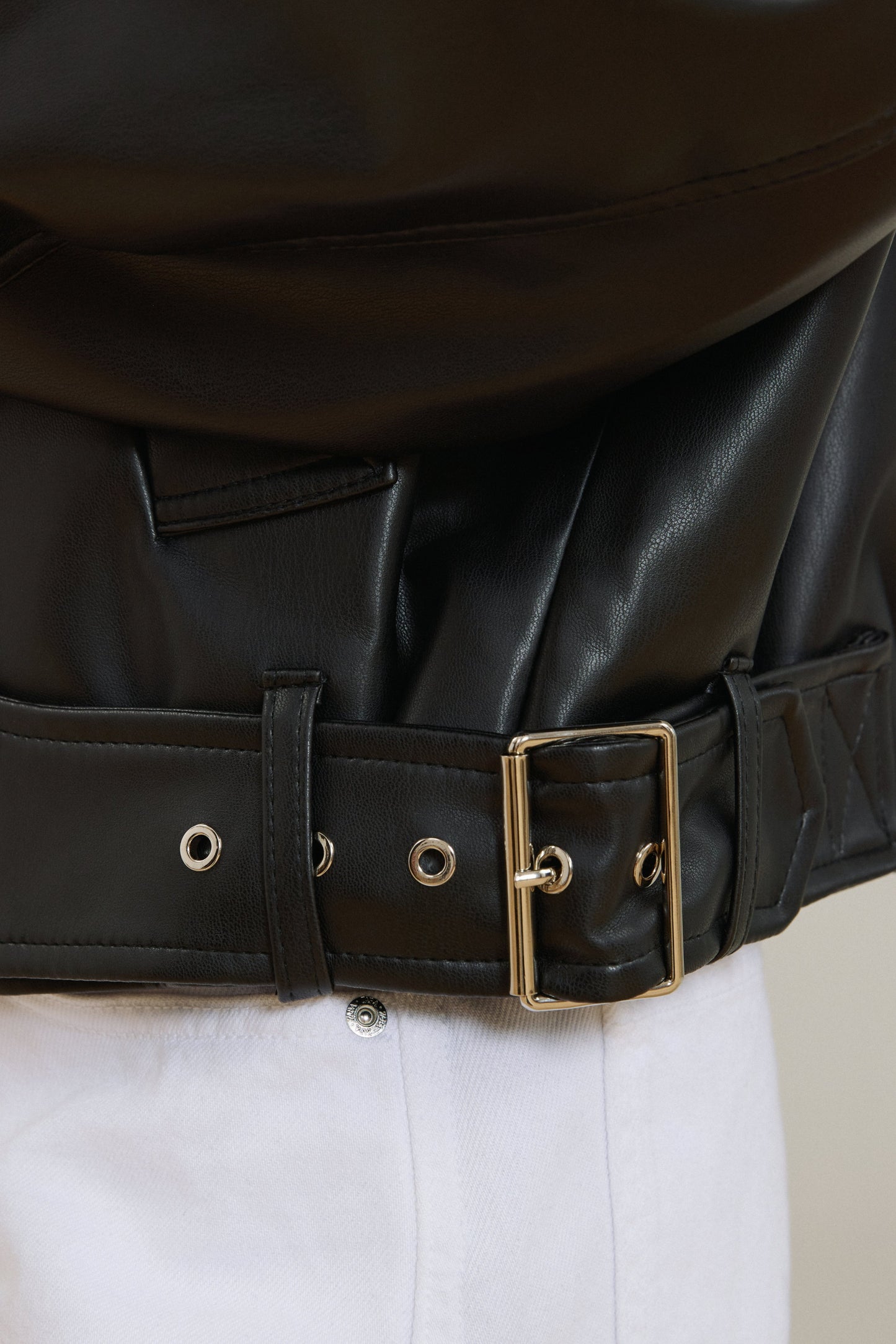 Detailaufnahme des Gürtels am unteren Saum der schwarzen Lederjacke