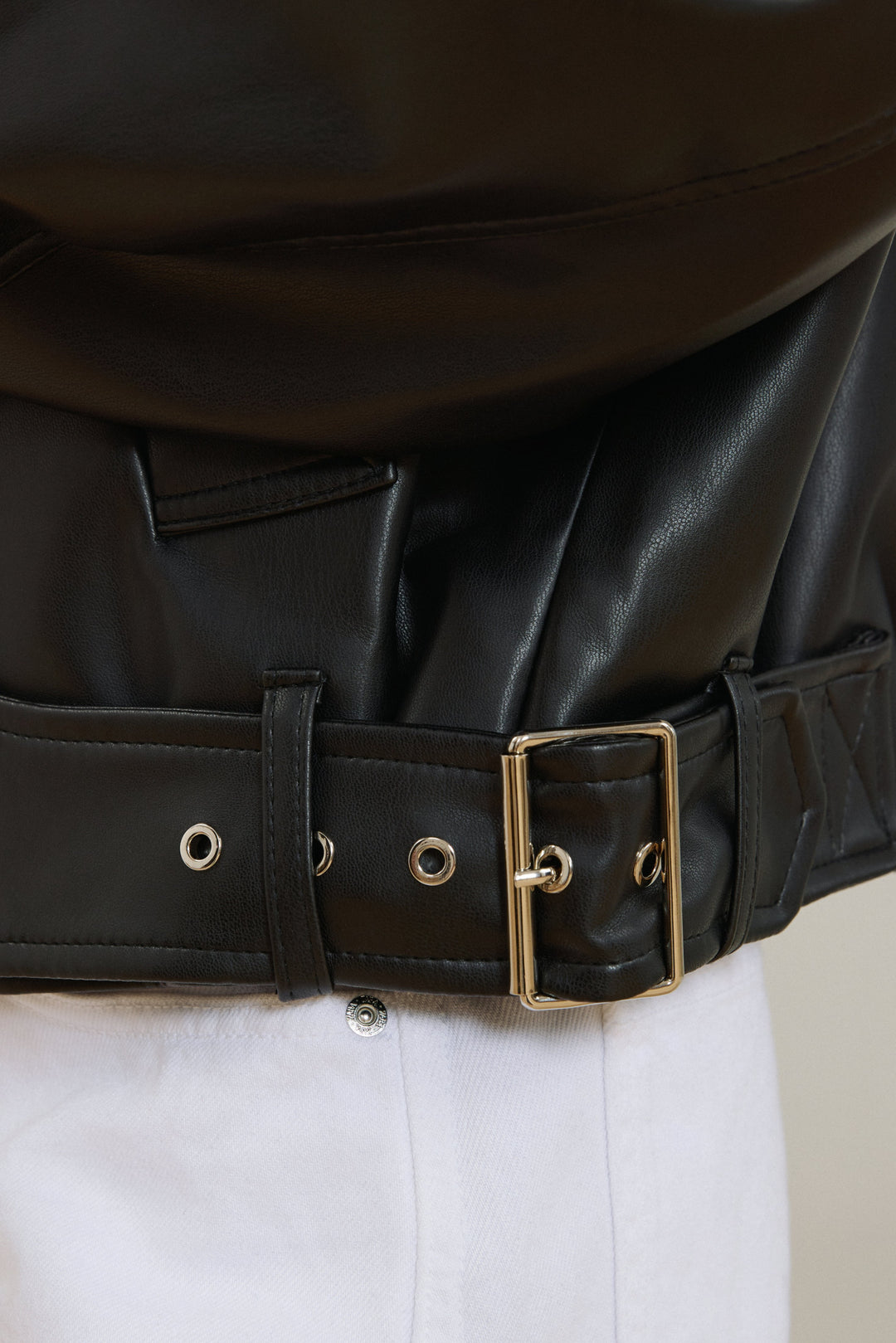 Detailaufnahme des Gürtels am unteren Saum der schwarzen Lederjacke
