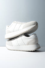 Zwei gestapelte weiße Damen-Sneaker aus weichem Echtleder und Velours.