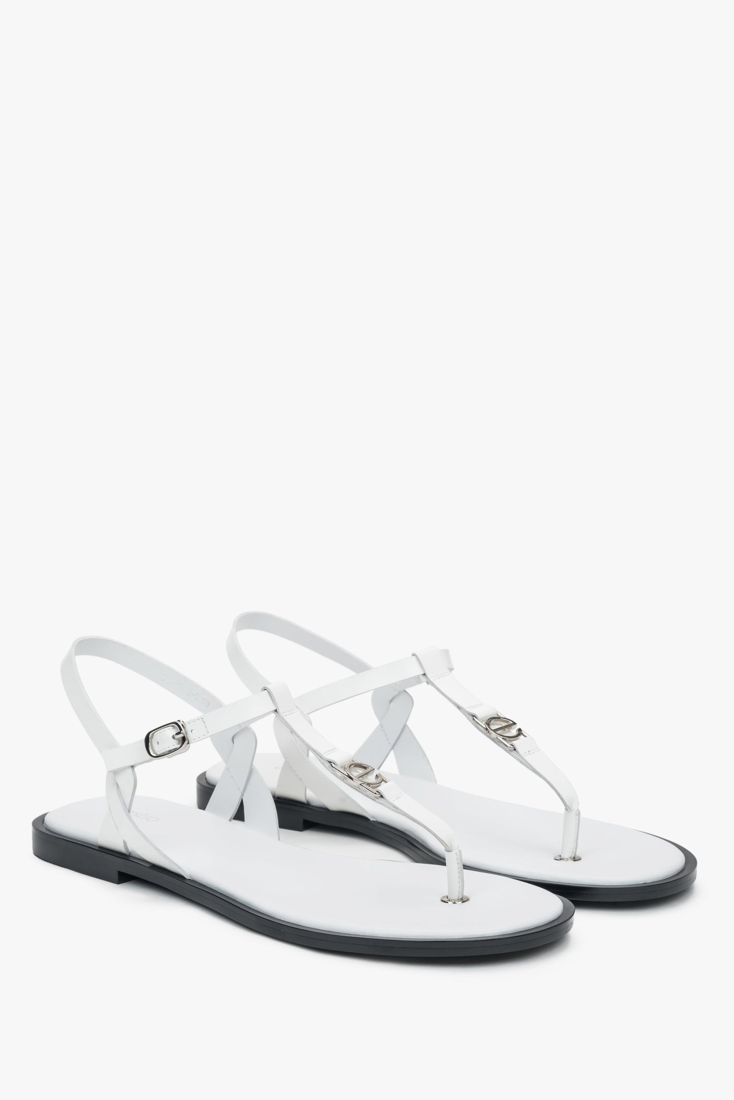 Schrägansicht des Paares weißer Leder-Sandalen mit feinem Fesselriemchen