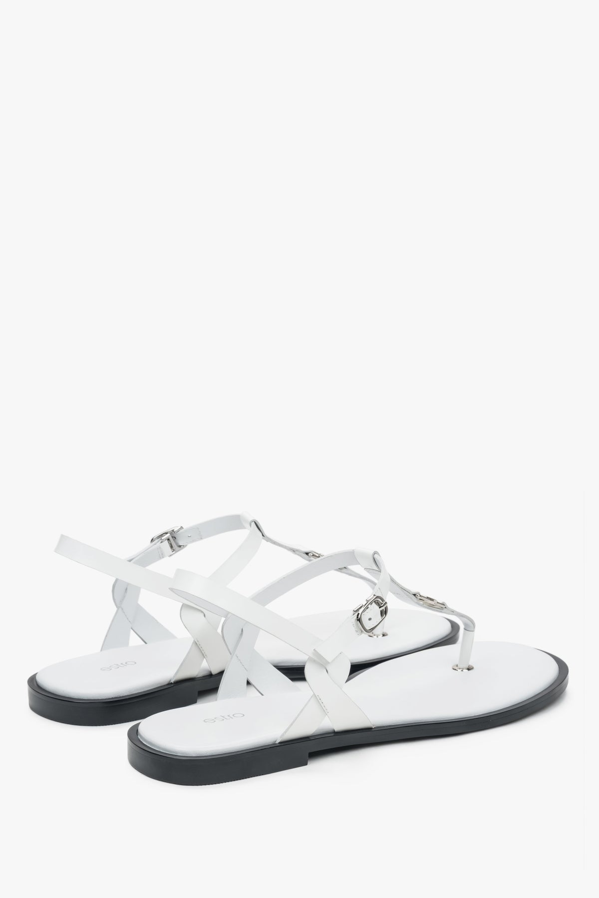 Rückwärtige Schrägansicht der weißen Sommer-Sandalen mit Fokus auf die flache Sohle